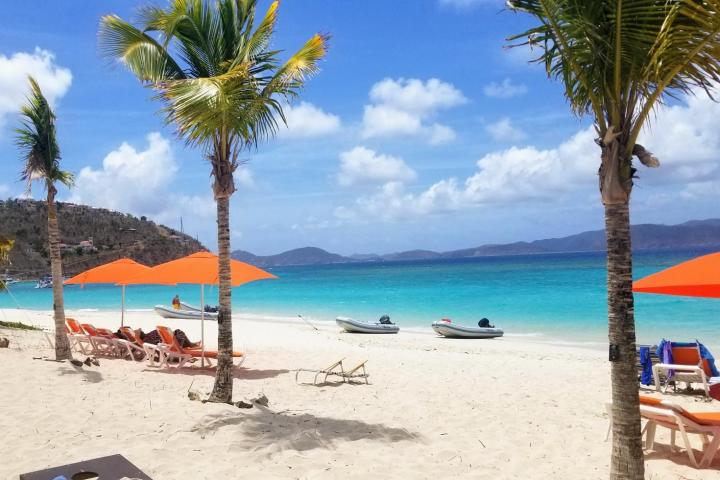 a group of lawn chairs sitting on top of a sandy beach