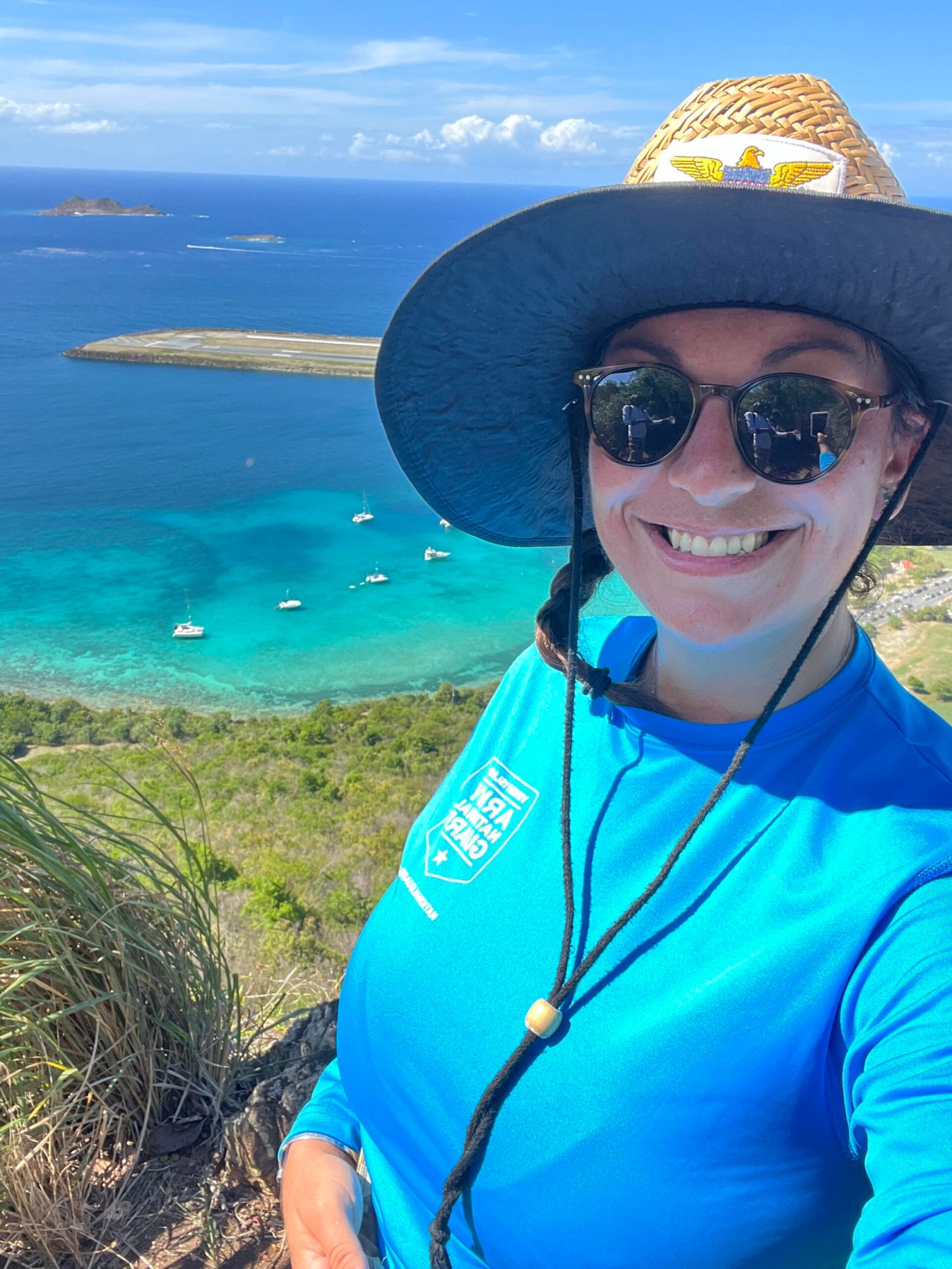 tara 1 a woman wearing a hat and sunglasses in front of a body of water