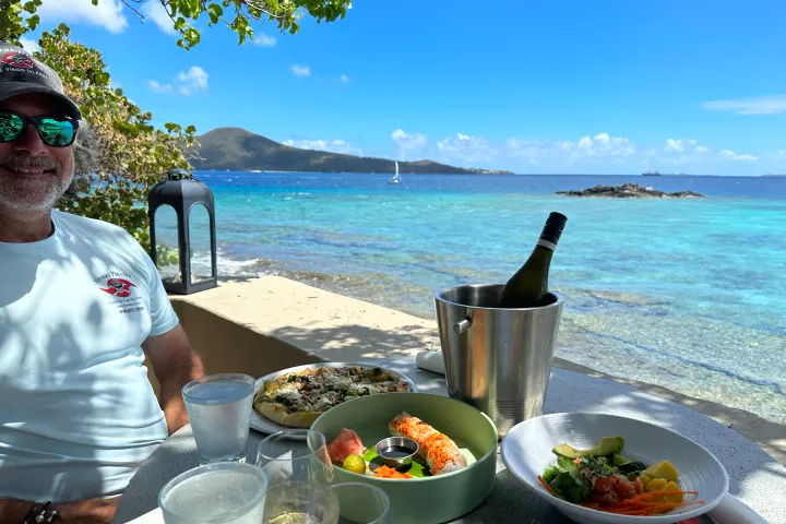 a man and a woman sitting at a table with food and water