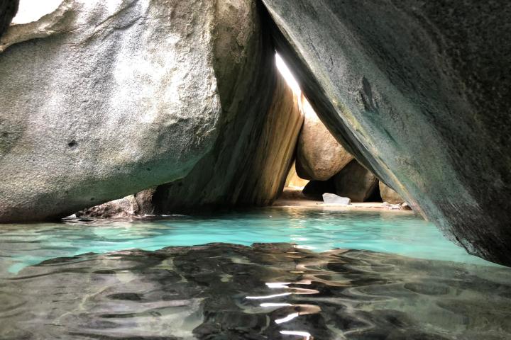a close up of a rock near the ocean with Virgin Gorda in the background