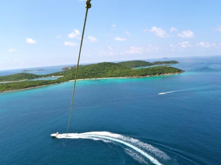 Aerial view of a boat making a wake near lush green islands in clear blue water.