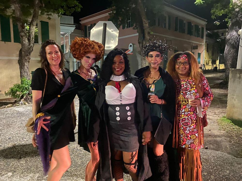 Five people in Halloween costumes smiling and posing outside at night.