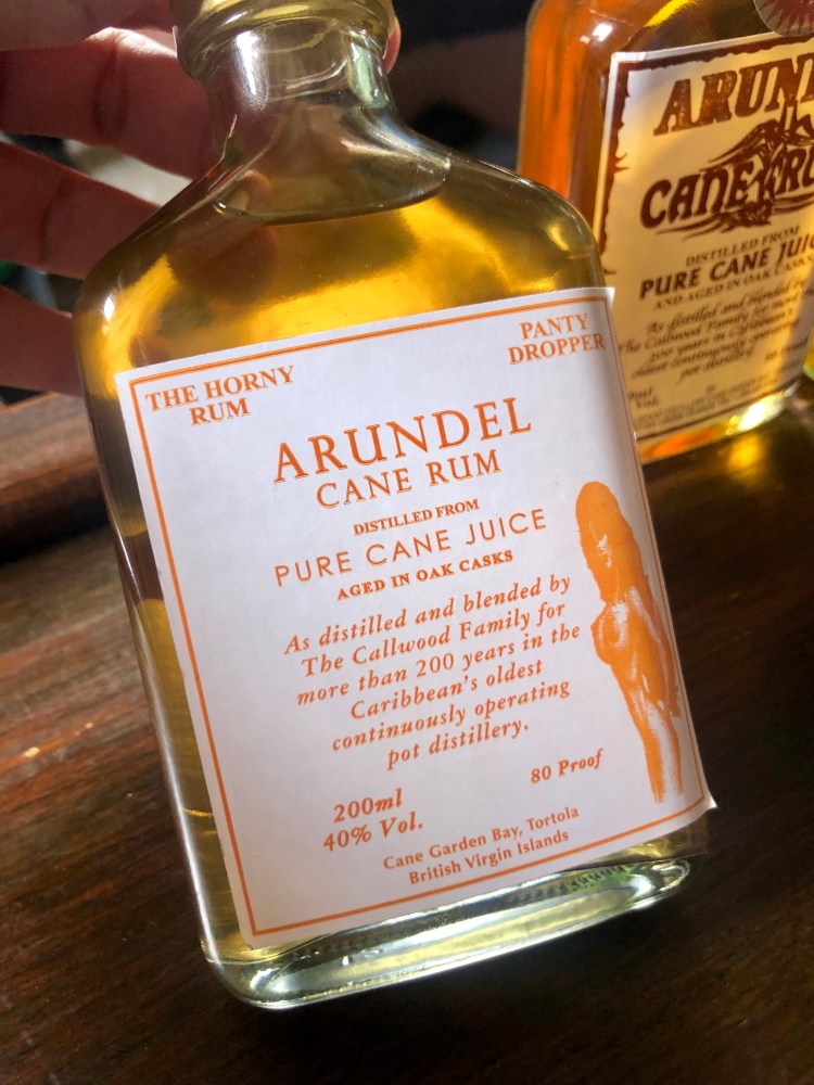 Close-up of a 200ml Arundel Cane Rum bottle with an orange label on a wooden surface.
