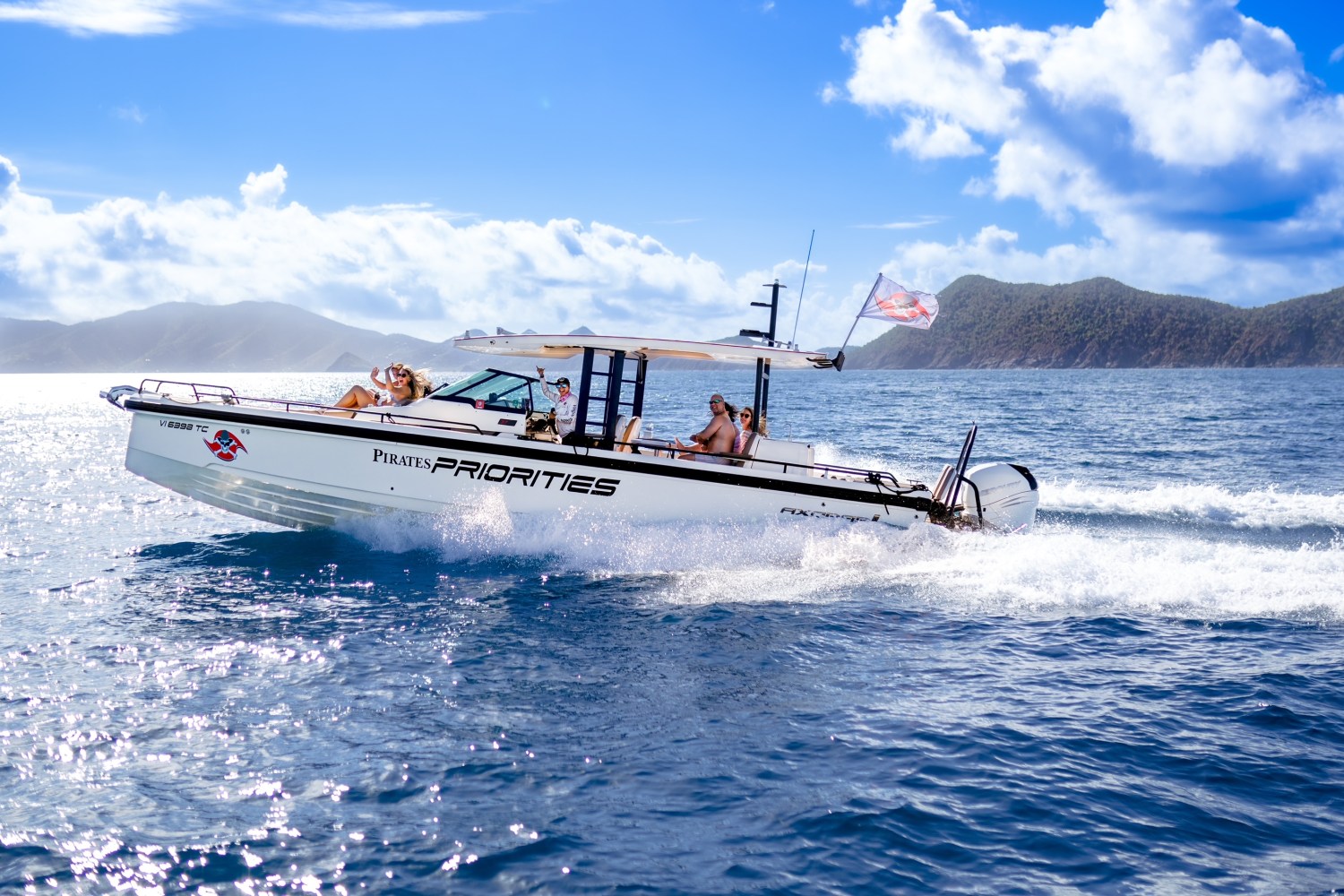 Motorboat with people on board cruising on sea near mountains under blue sky.