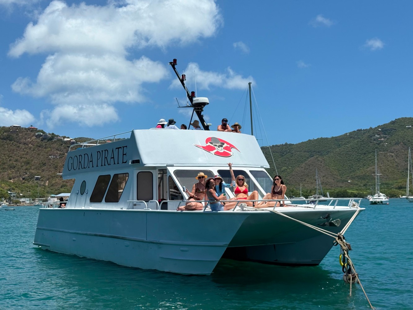 Group relaxing on a boat named 'Gorda Pirate' in a sunny bay.