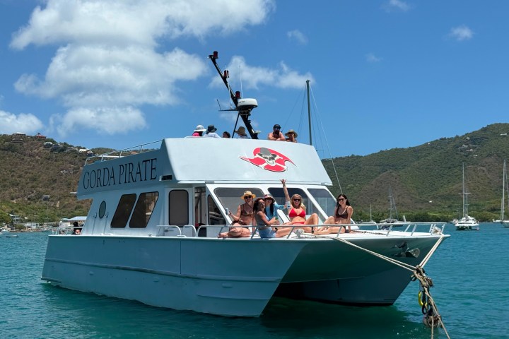 Group relaxing on a boat named 'Gorda Pirate' in a sunny bay.