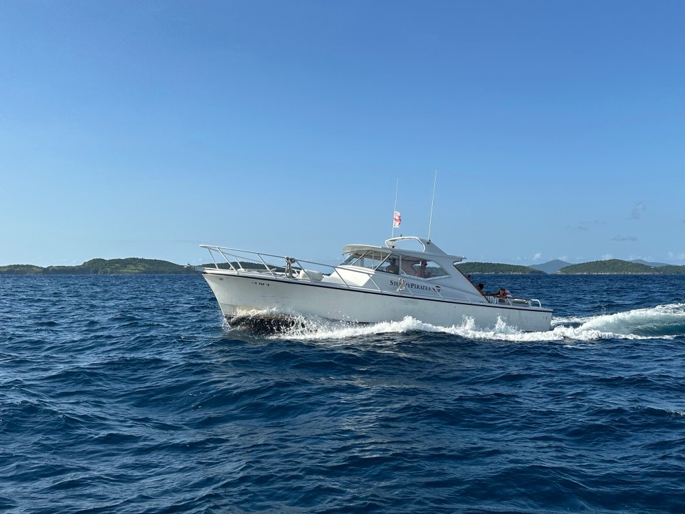 White motorboat cruising on blue ocean with small islands in the background.