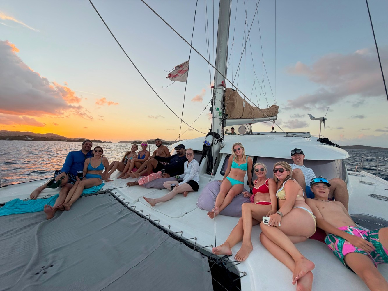 Group of people relaxing on a catamaran at sunset.